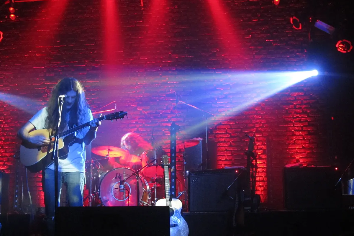 A guitarist on the Niceto Club stage against a red-lit brick wall